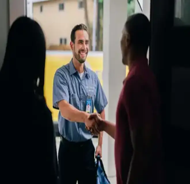 A Woman and Man Pictured from Behind in an Open Doorway and the Man Shaking Hands with a Mr. Electric Tech Outside the Door.