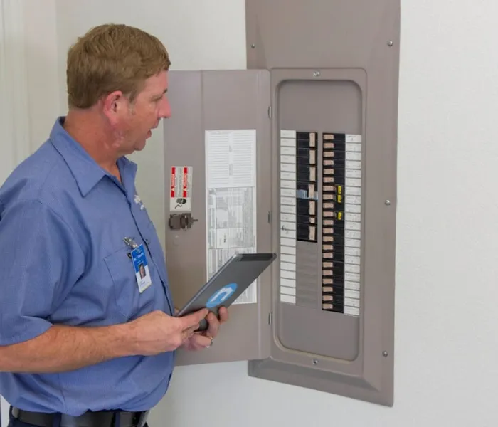 An mre employee inspecting an electrical panel.