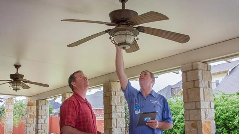 Mr. Electric service professional inspecting porch ceiling fan with homeowner.