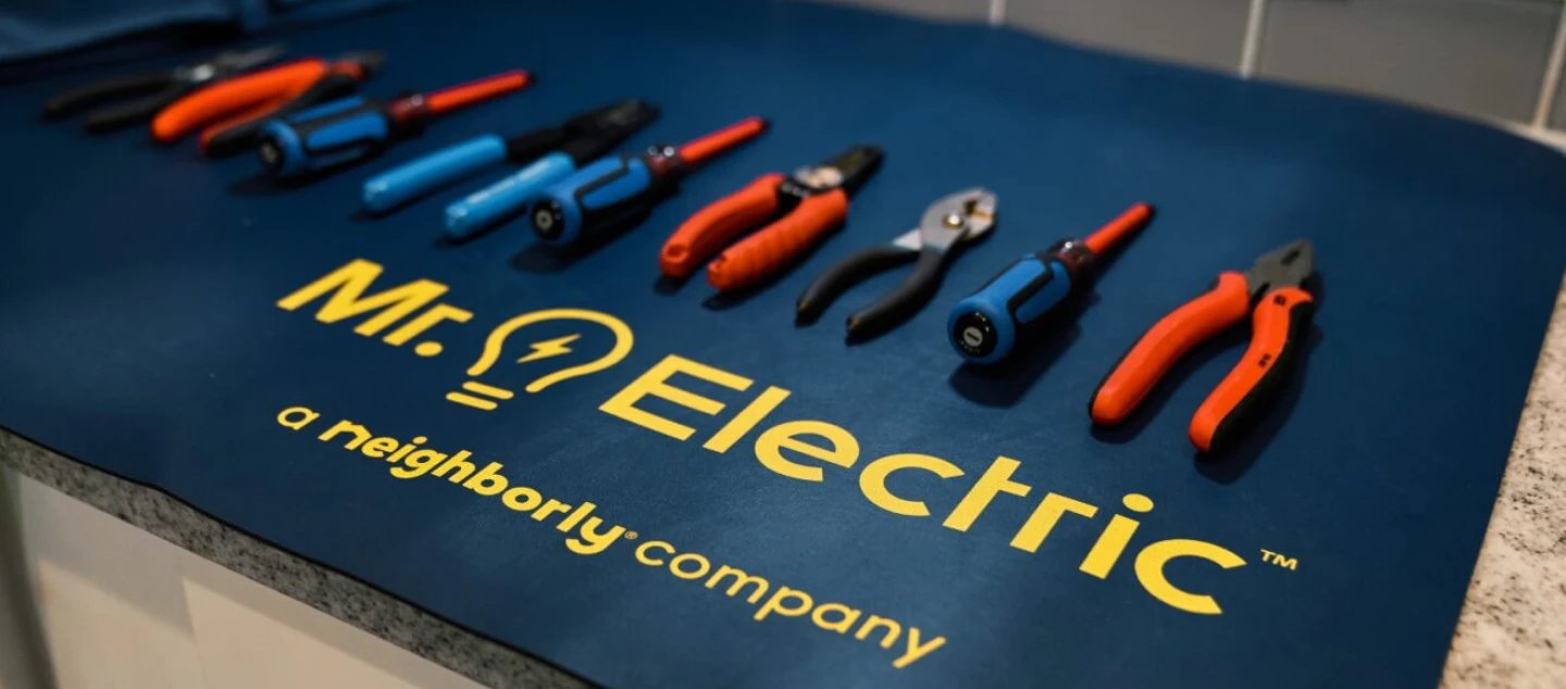 A row of electrical repair tools on a blue Mr. Electric placemat