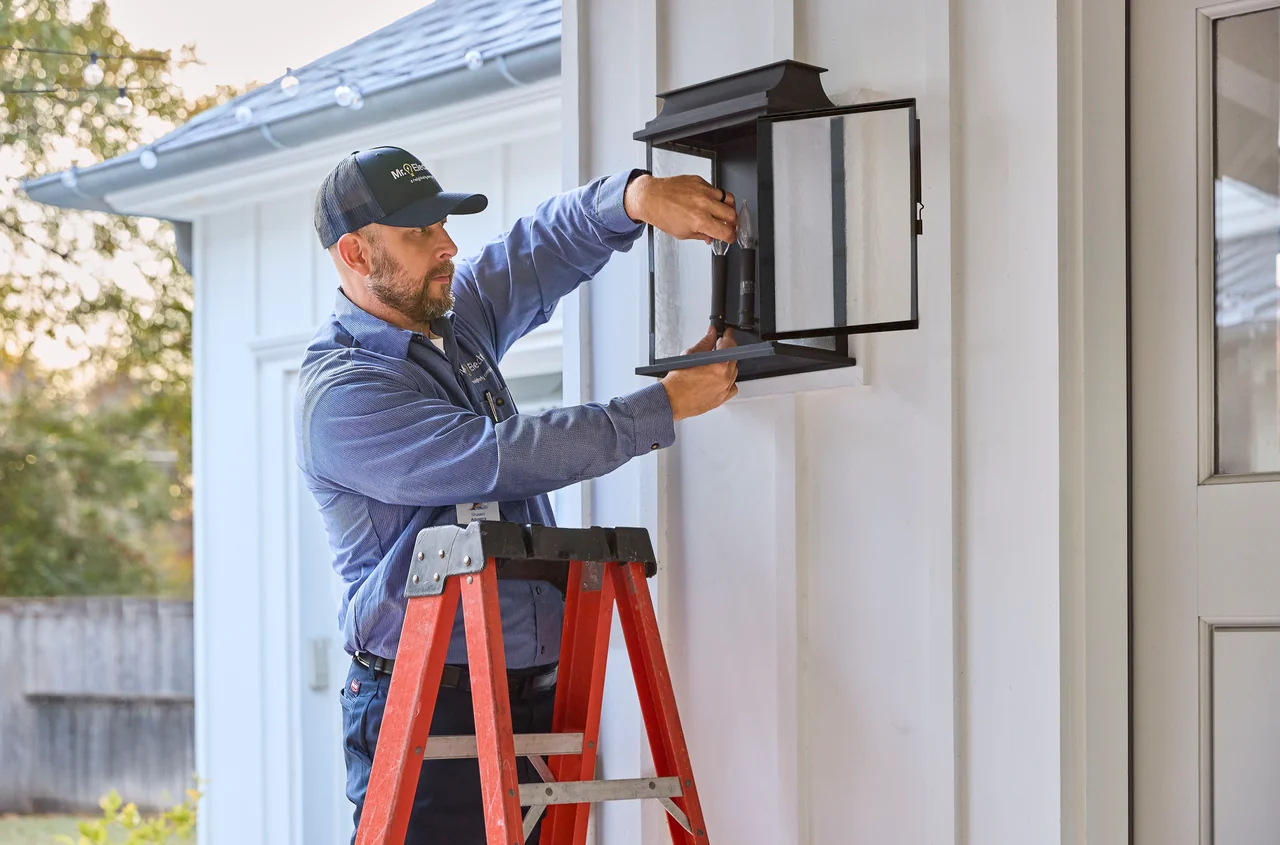 Mr. Electric service professional repairing an exterior house light sconce