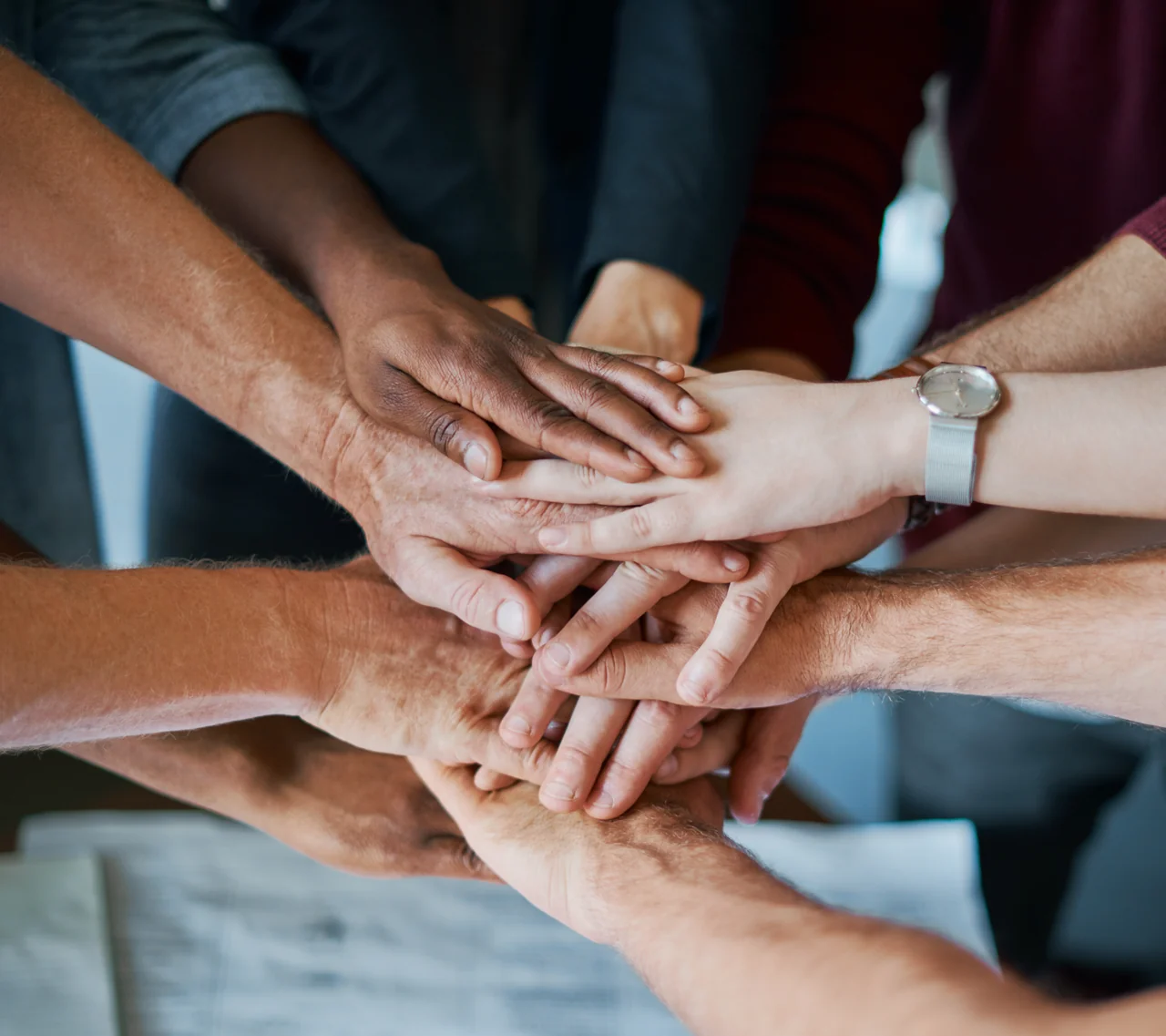 Close-up of a group of people stacking their hands together in a huddle
