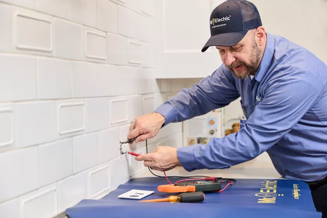 Mr. Electric professional troubleshooting a kitchen outlet with a multimeter