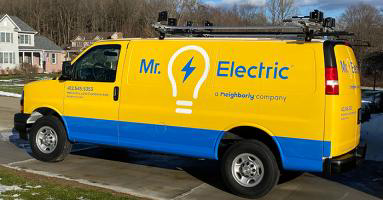 A blue and yellow work van branded with the logo for Mr. Electric.