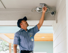 Electrician installing an outdoor security camera.
