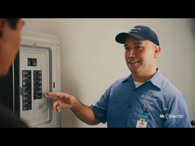 A Mr. Electric expert showing a client their house's power box.