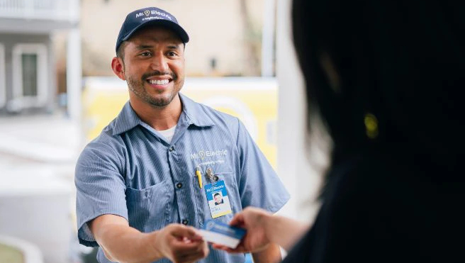 Mr. Electric electrician handing business card to customer.