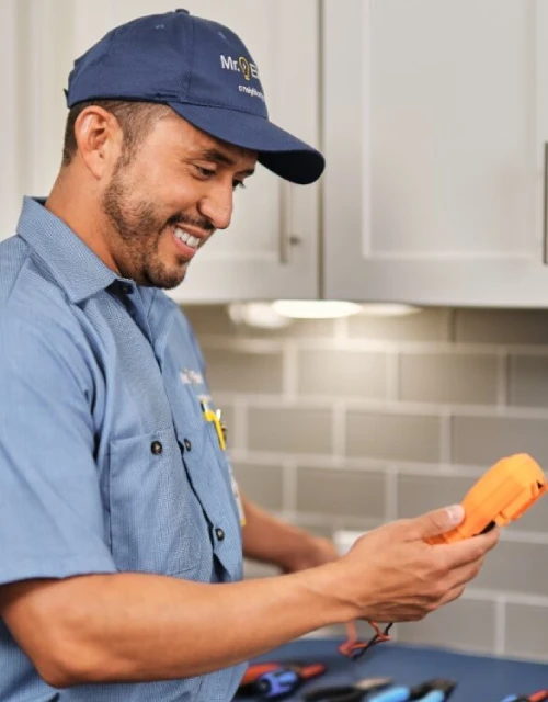 Mr. Electric technician holding a tool in the kitchen.