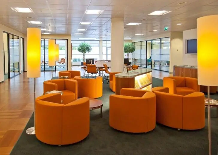 Lobby of an office building with orange chairs.