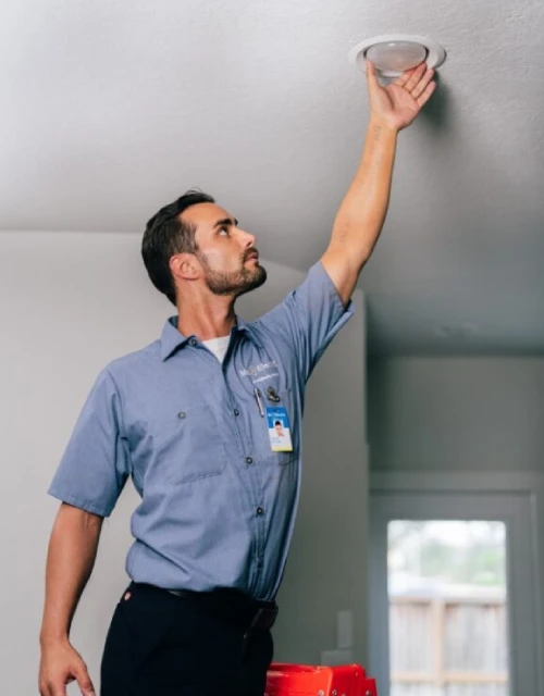 Electrician reaching for light bulb.