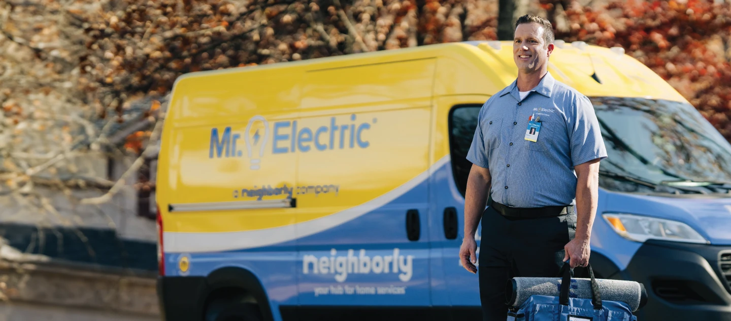  Male electrician standing in front of Mr. Electric branded van.