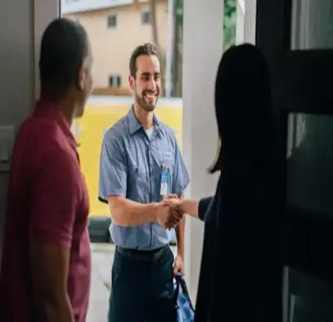 A Man and Woman Pictured from Behind in an Open Doorway and the Woman Shaking Hands with a Mr. Electric Tech Outside the Door.