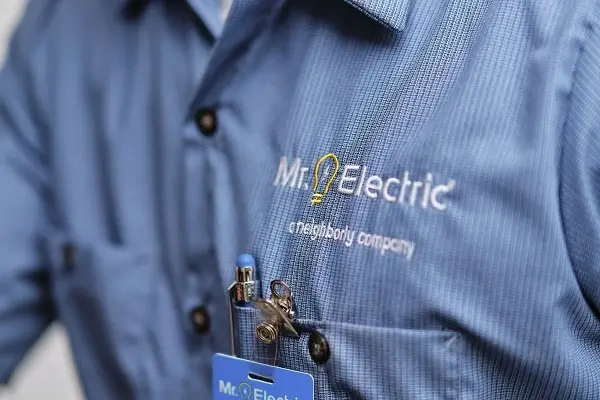 Close-up of a man’s chest in a blue work shirt with a Mr. Electric logo and a pen in the pocket. 