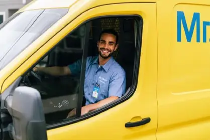 Mr. Electric electrician in the front seat of a yellow Mr. Electric van.