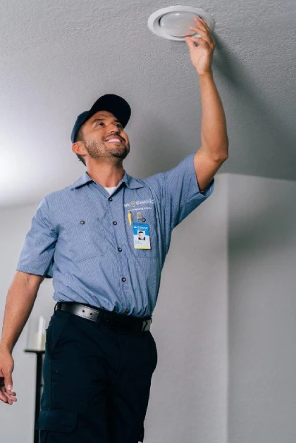 Mr. Electric electrician replacing a light bulb.