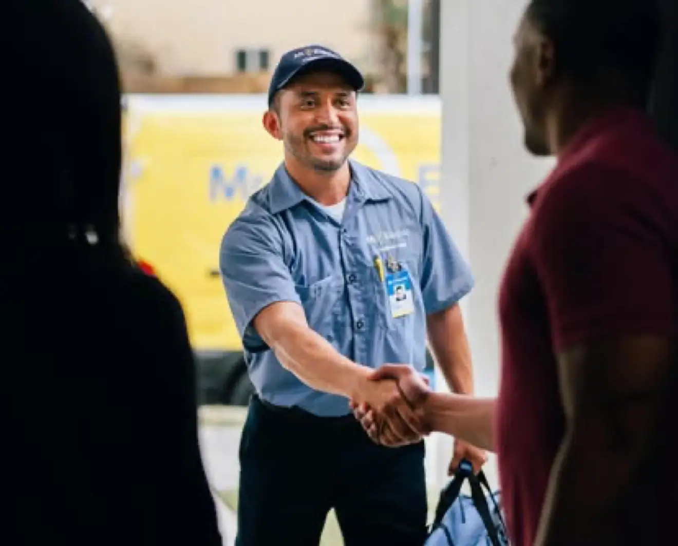 Mr. Electric technician shaking hands with a customer at their door.