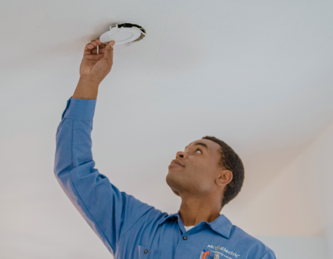Mr. Electric technician installing a smoke and carbon monoxide detector.
