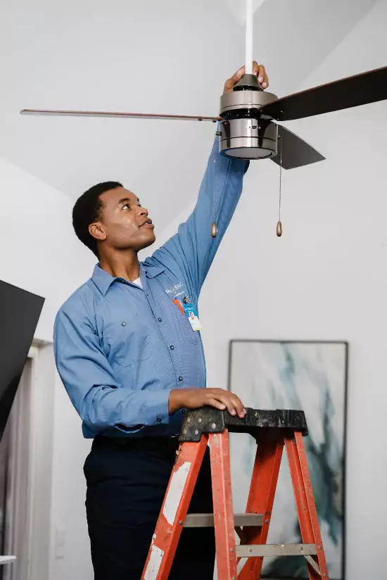A Mr. Electric electrician installing a ceiling fan.