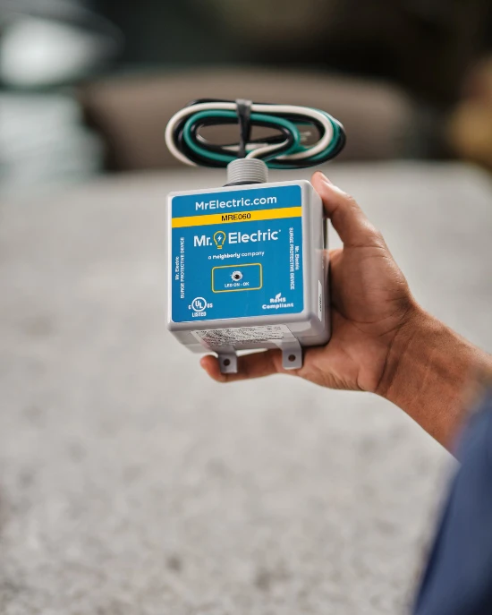 Mr. Electric electrician holding a whole-house surge protector