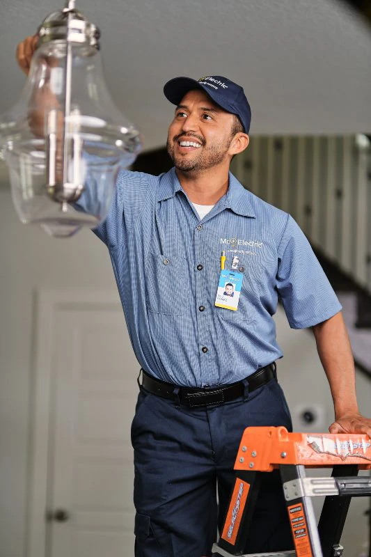 Mr. Electric electrician on a ladder performing a light fixture repair