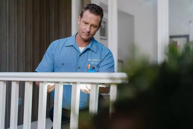 A Mr. Electric electrician installing landscape lighting on a piece of deck railing