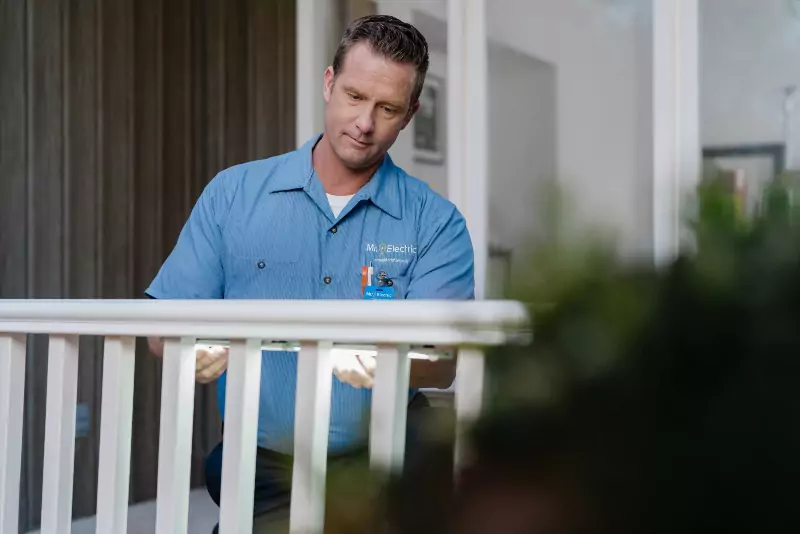 A Mr. Electric electrician installing landscape lighting on a piece of deck railing in Houston, TX.