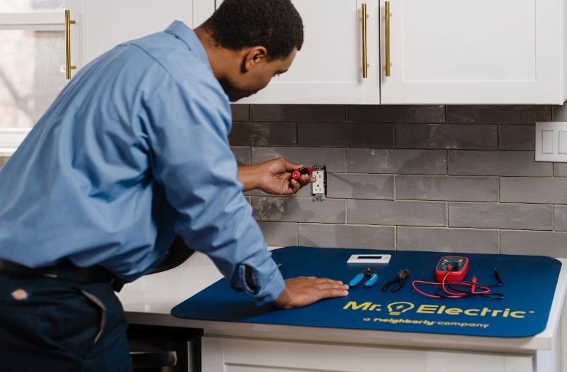 A Mr. Electric electrician removing an old outlet to install a USB Outlet