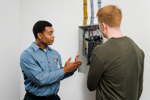 An electrician shows a customer their electrical panel.