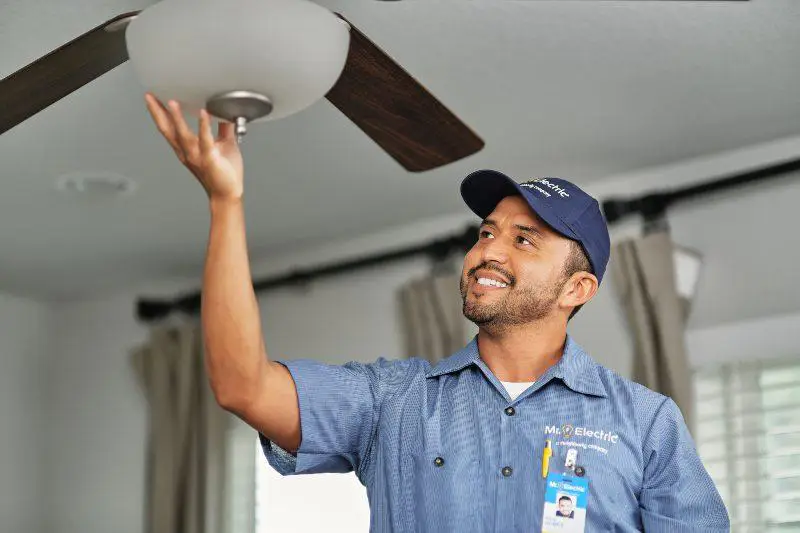 A Mr. Electric electrician installing a ceiling fan