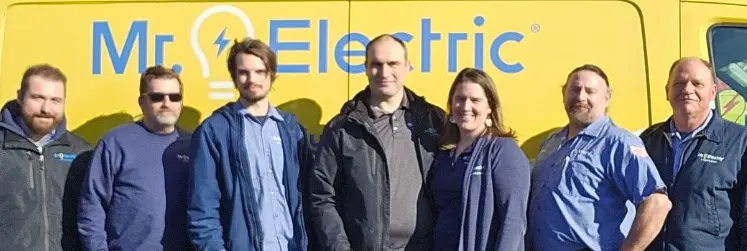 Row of smiling Mr. Electric of Hillsboro associates standing outdoors in front of Mr. Electric truck.