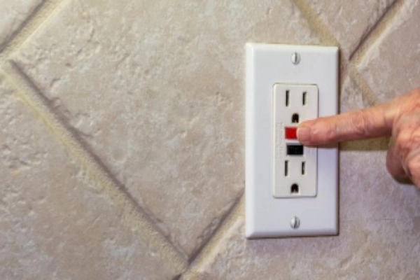 Close-up of a hand resetting a GFCI outlet that has been tripped.