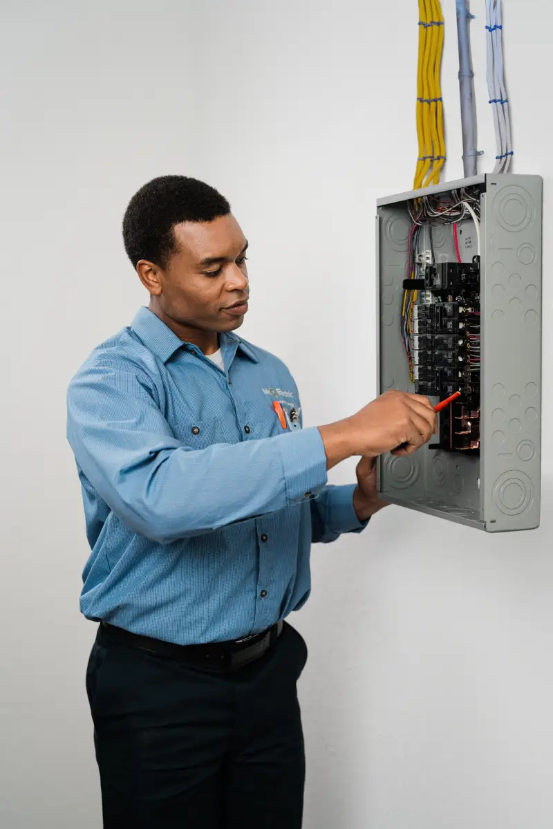 A Mr. Electric service professional speaking with a homeowner next to a breaker.