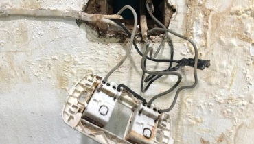 Outlet pulled out of the wall to show electrical wiring damaged by water