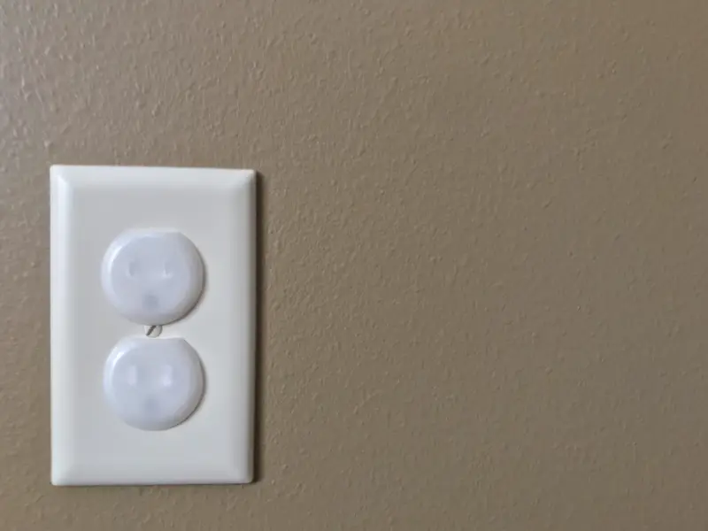 A close-up of an electrical outlet with childproof coverings.