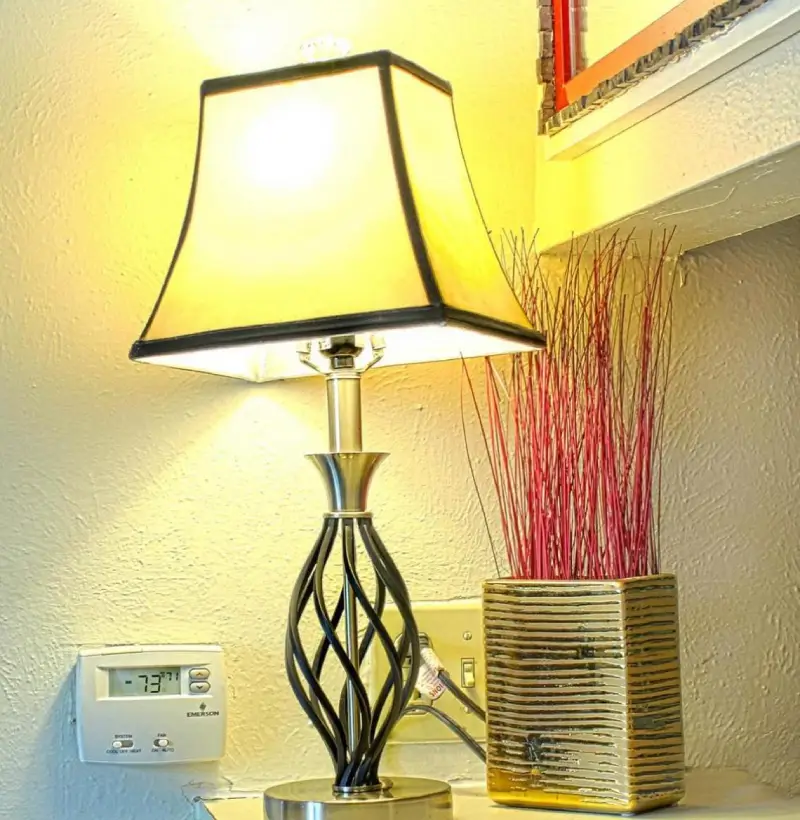 Photograph of a fan on a table next to a thermostat.