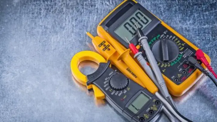 Digital clamp meter and electric tester multimeter on metallic background.