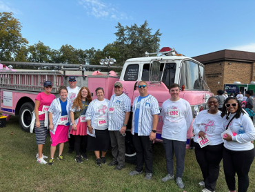 A group of people standing in front of a pink fire truck.
