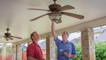 Mr. Electric service professional inspecting porch ceiling fan with homeowner.