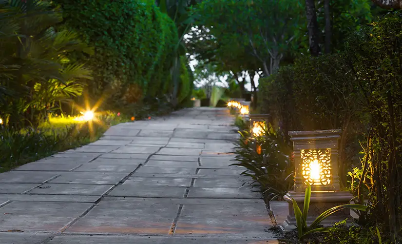 A picture of path lights on each side of a walkway surrounded by landscape.