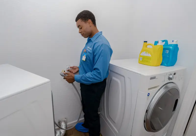 A Mr. Electric service professional holding a cord to an appliance in the laundry room.