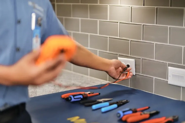 Close up of Mr. Electric electrician using a Digital Multimeter DC AC Voltmeter to test outlet voltage.