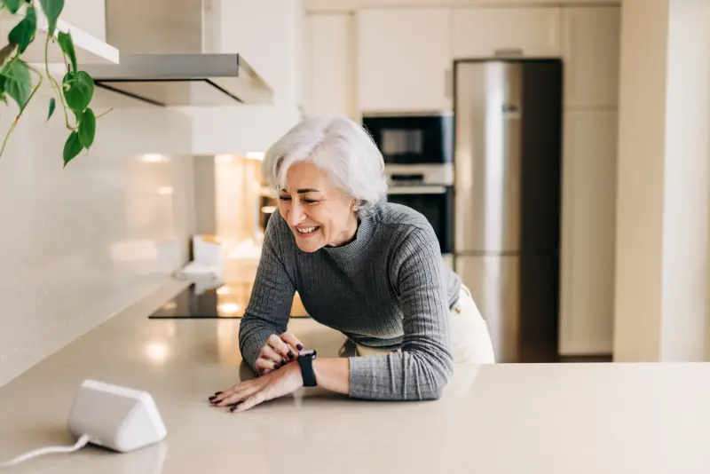 Senior woman speaking to her smart home device in her kitchen
