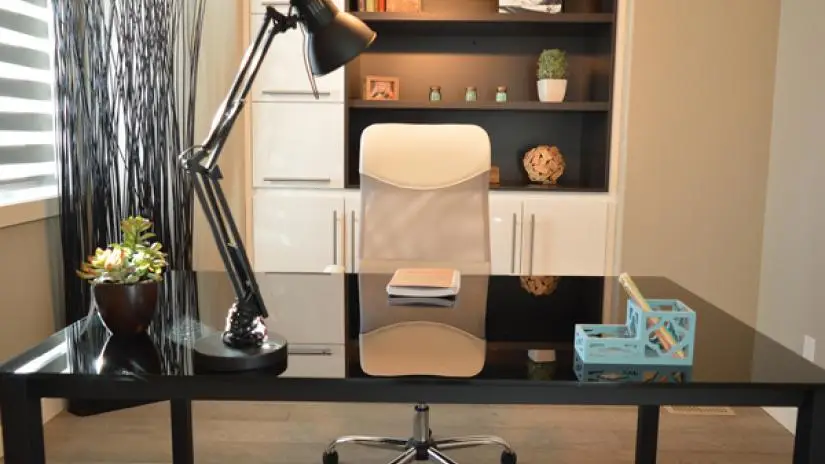 Home office desk and chair with lamp and bookshelf.