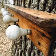 Wood with light bulbs attached to create a coat rack.