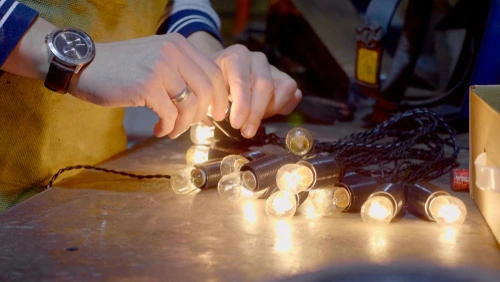 Close-up of hands fixing Christmas lights.