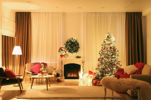 Beautiful living room interior with burning fireplace and Christmas tree in evening.