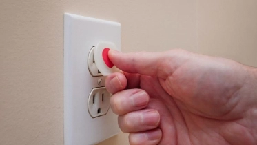Person inserting a child protection cover on a wall outlet in a residential home.