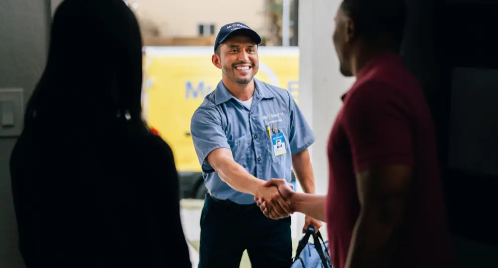 An electrician arrives to install an attic fan and shakes the customer's hand.