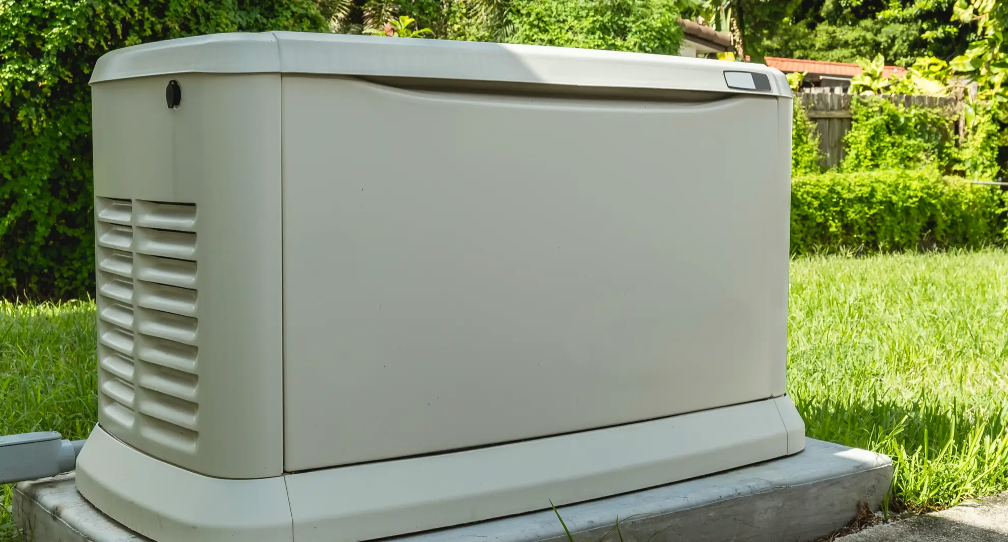 Outdoor commercial backup generator unit mounted on concrete pad in landscaped area