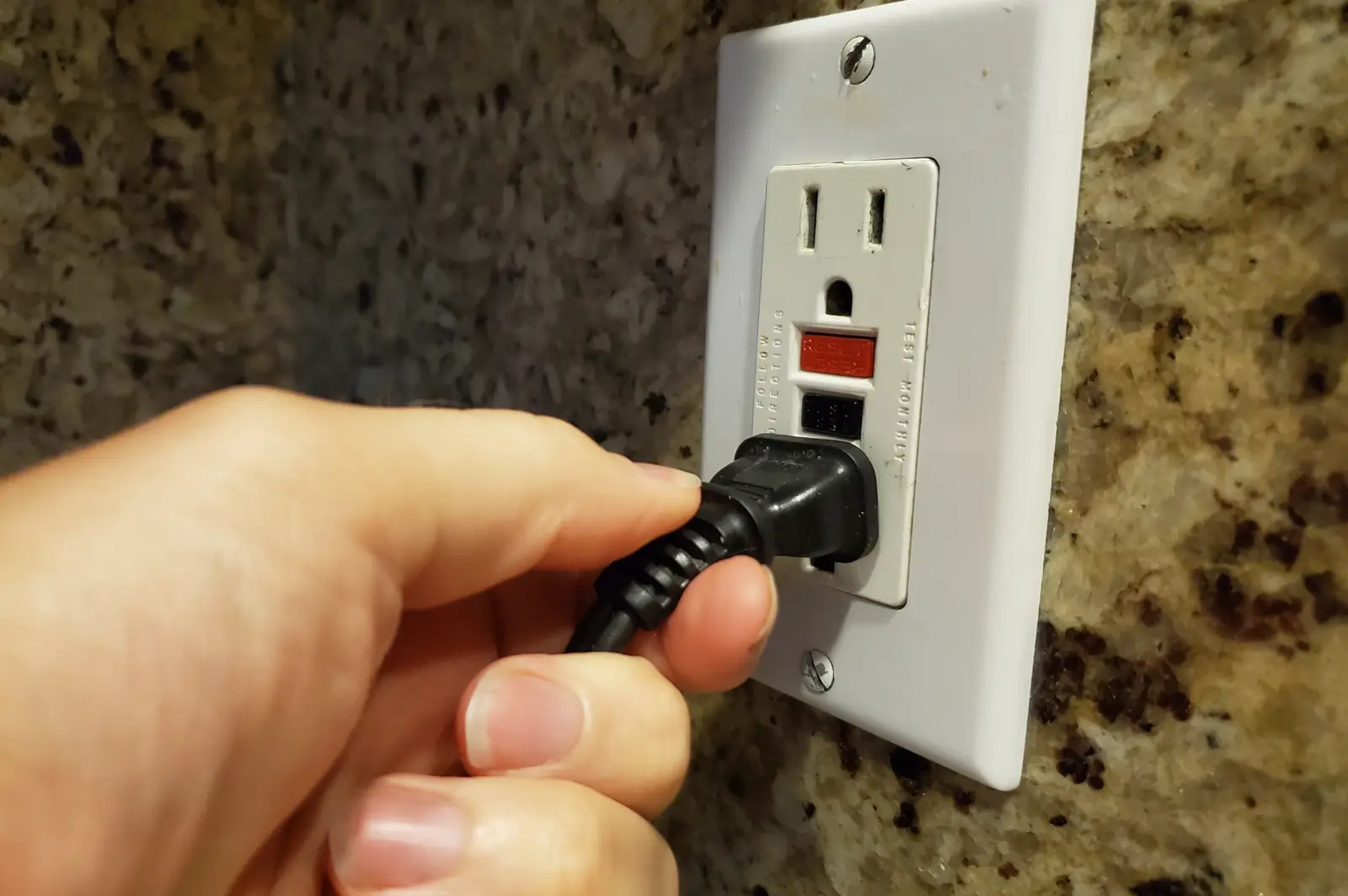 A power cord being plugged into a GFCI outlet